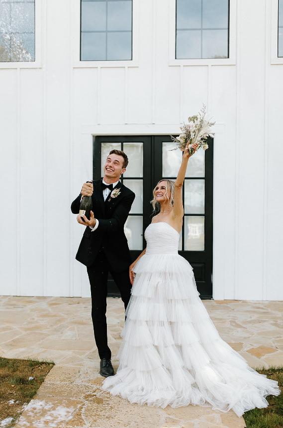 A classic yet modern bride and groom pop the champagne at The Monroe on 415th wedding venue in McMinnville, TN located near Nashville. 